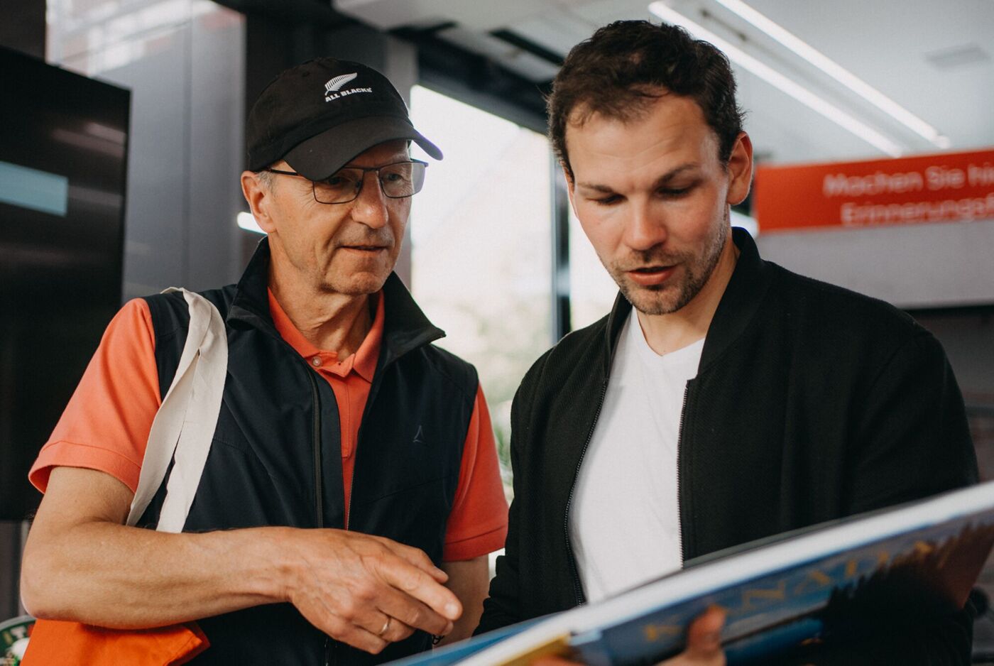 Zwei Männer betrachten gemeinsam ein aufgeschlagenes CEWE FOTOBUCH.