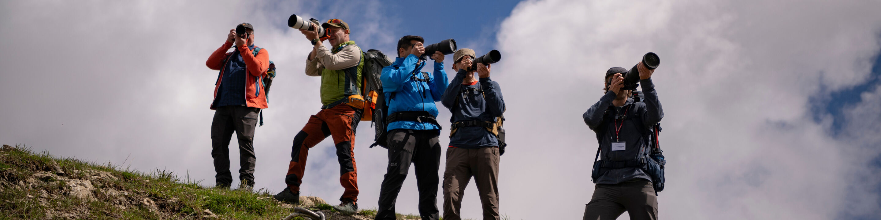 Fünf Fotografen stehen auf einem Hügel und fotografieren die Landschaft.