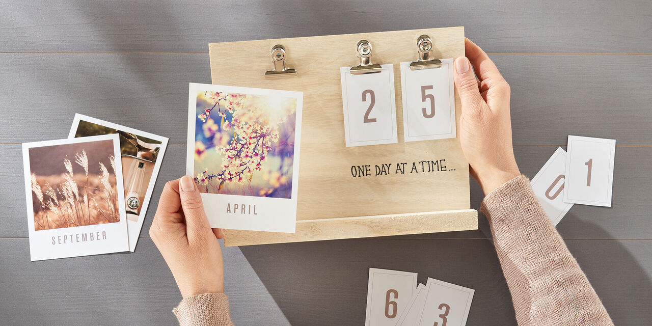 Personen sortieren Kalenderkarten und persönliche Fotos auf einem Holzständer