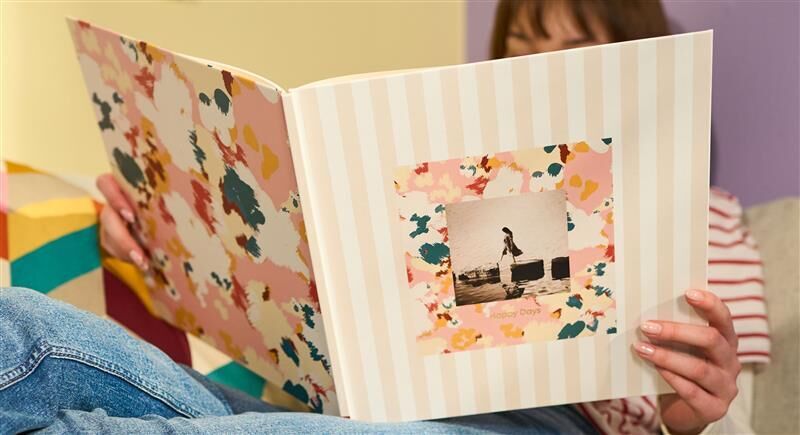 Eine Person hält ein aufgeklapptes CEWE FOTOBUCH in den Händen.