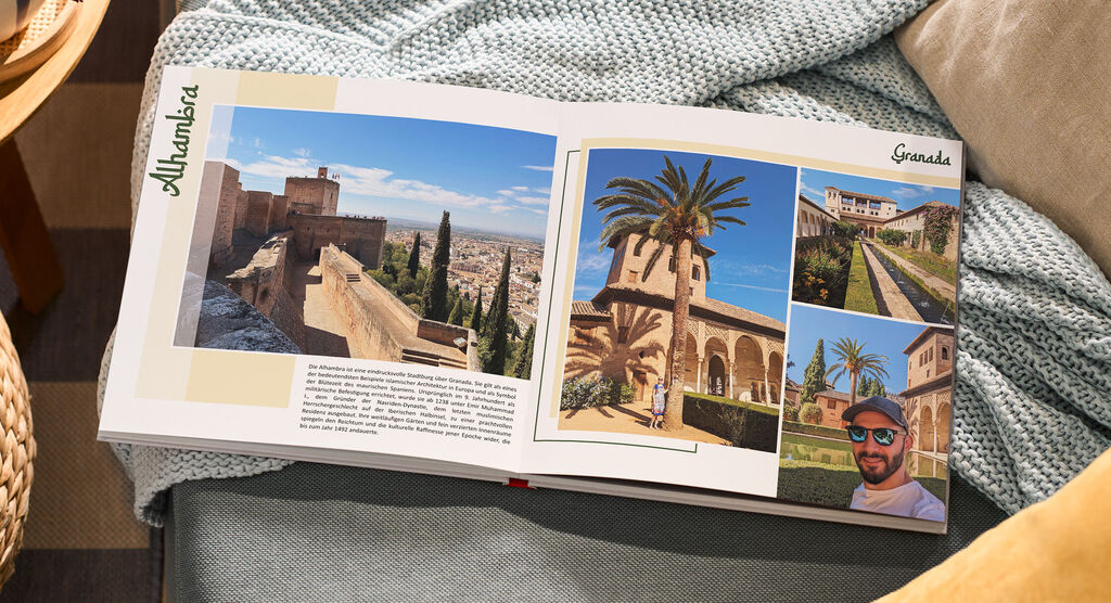 Auf einem Sofa liegt ein aufgeschlagenes Fotobuch. Die Fotos zeigen Gebäude und Landschaft in Andalusien.