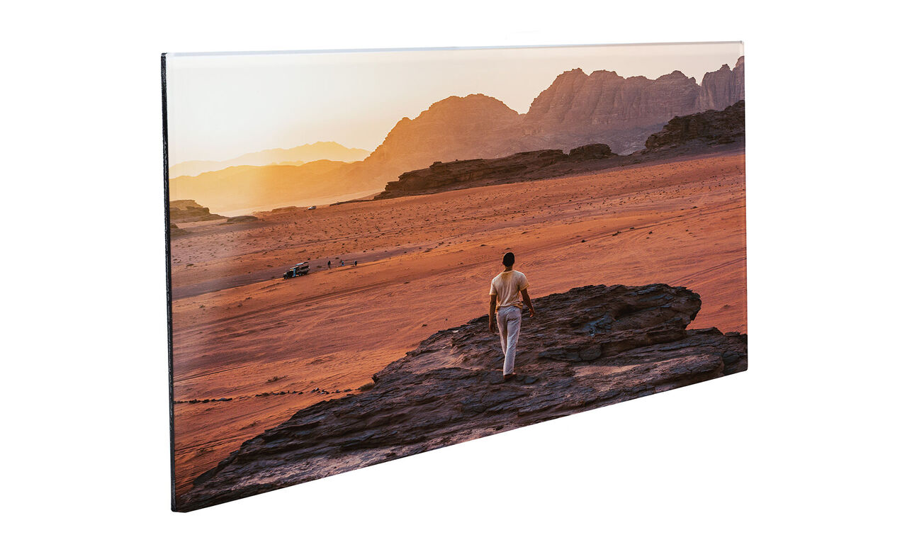 Ein Mensch geht in der goldenen Wüste bei Sonnenuntergang. Die Landschaft zeigt sanfte Hügel und warme Farben.
