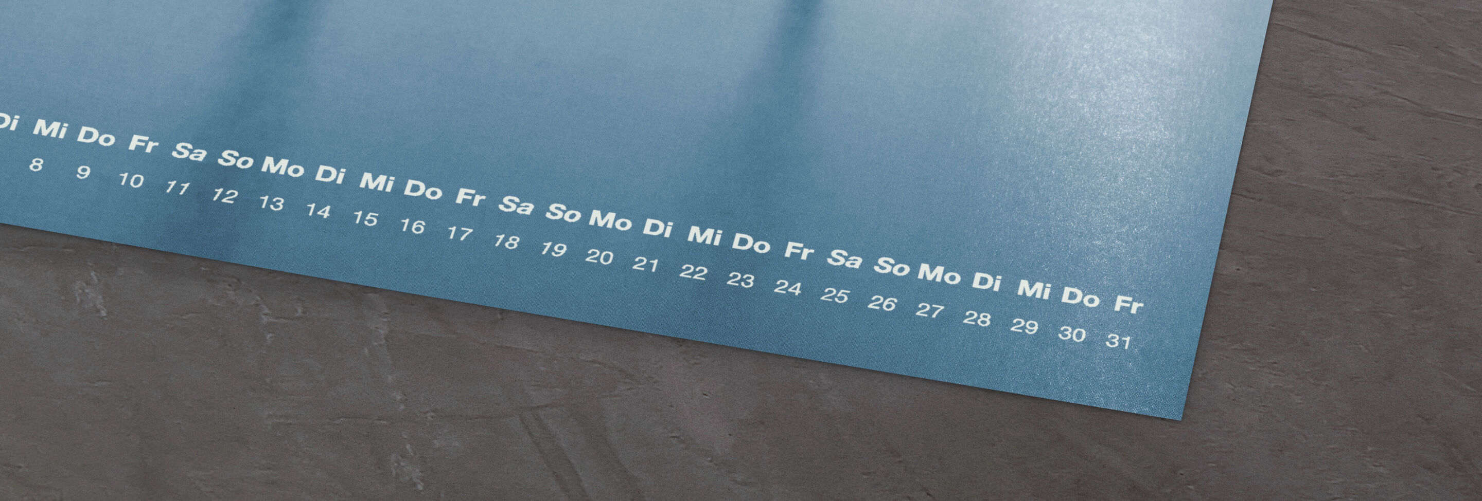 Ein stilvoller CEWE Fotokalender mit blauer Oberfläche und Wochentagen.