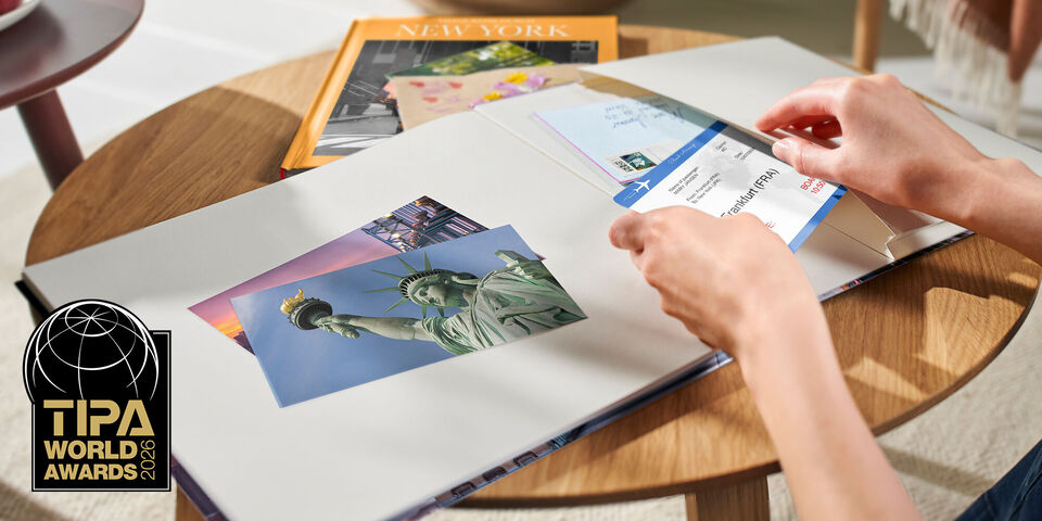 Eine Person schaut sich Fotos in einem CEWE FOTOBUCH an, das die Freiheitsstatue zeigt.