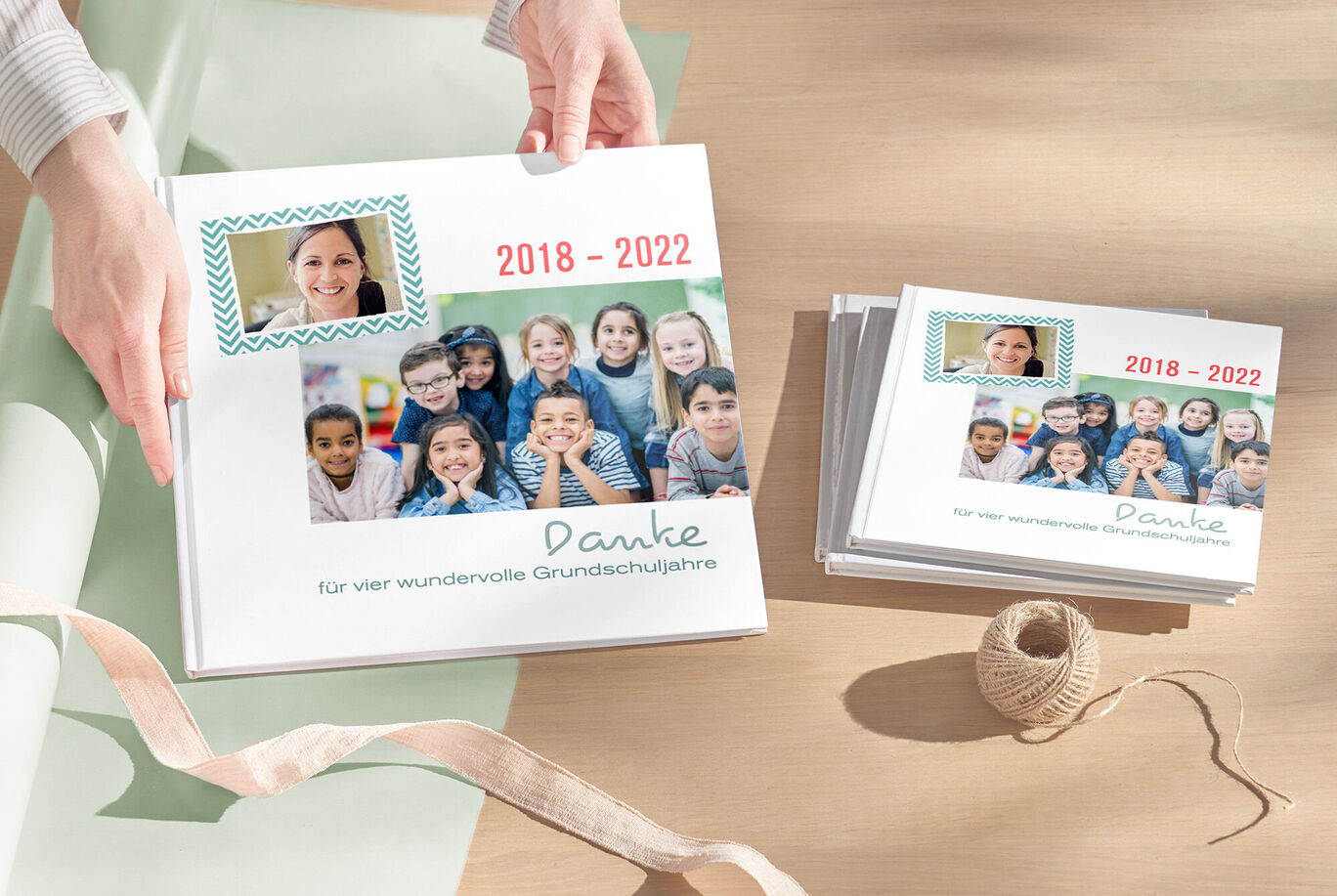 Ein liebevoll gestaltetes CEWE FOTOBUCH mit einer Dankesbotschaft für Grundschullehrer und Fotos von glücklichen Kindern. Es liegt auf einem Tisch mit Dekoration.