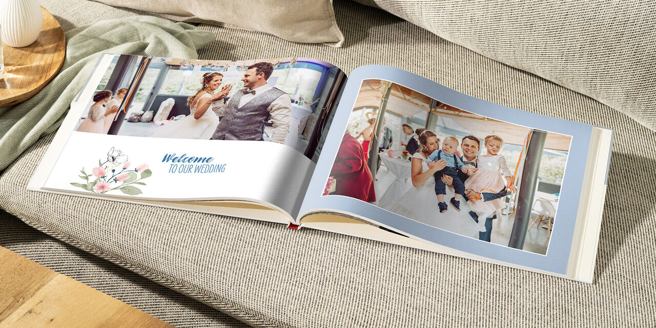Ein offenes Fotobuch auf einer Couch mit Hochzeitsfotos.