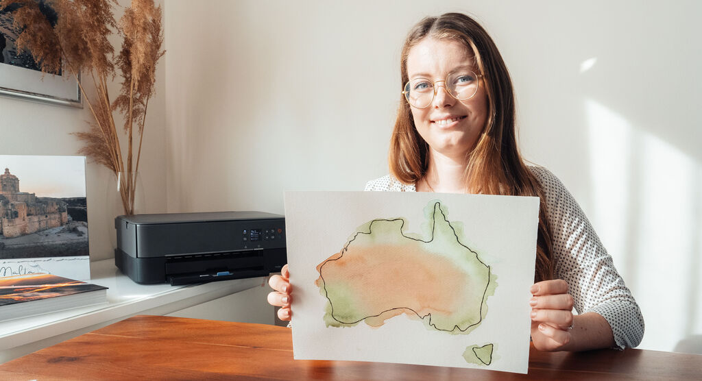 Eine Frau hält ein Aquarellbild von Australien in der Hand