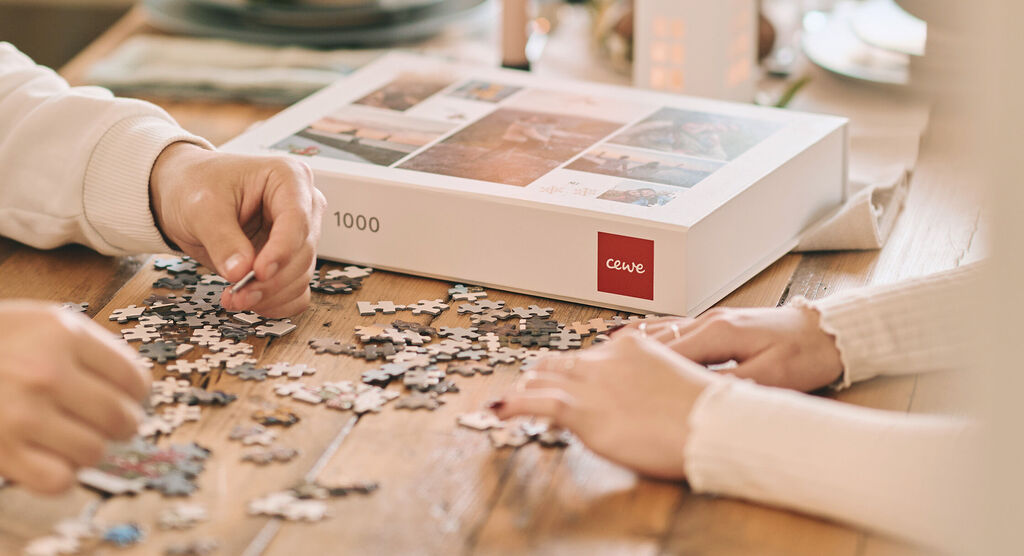 Hände legen Puzzlestücke auf einem Tisch.