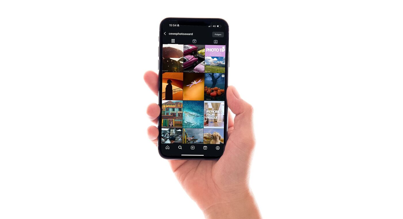 Die Hand einer Person ist zu sehen. Sie hält ein Smartphone fest, auf dem Bildschirm ist der CEWE Photo Award Account geöffnet.