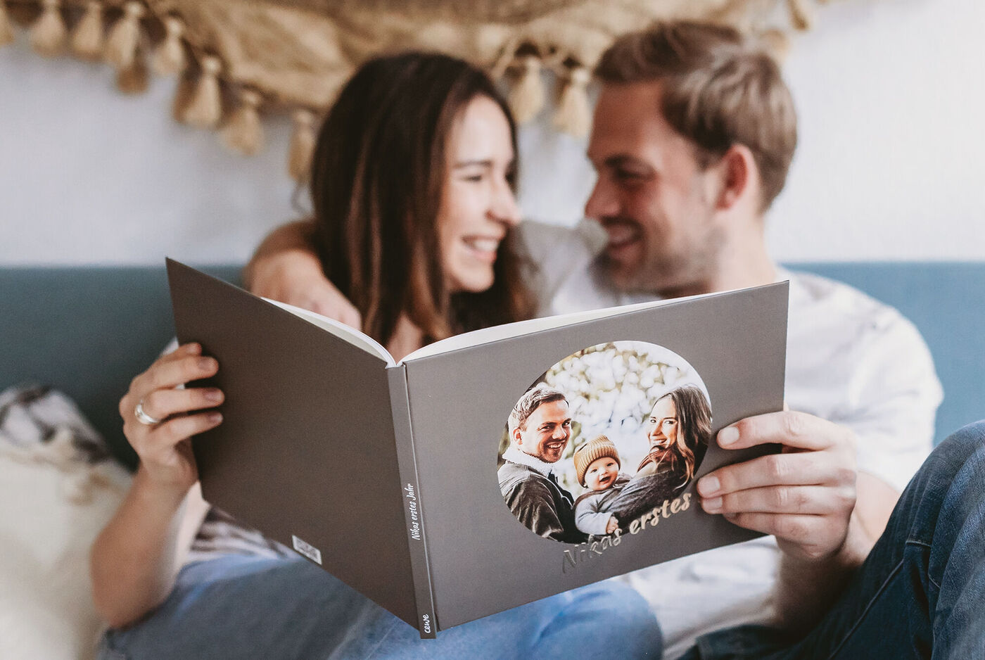 Ein Paar schaut glücklich in ein CEWE FOTOBUCH, um Erinnerungen zu erleben