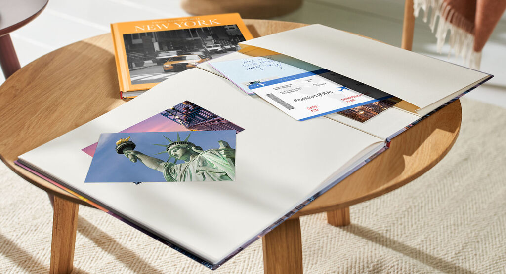 Offenes Fotobuch zeigt Statue of Liberty neben blanko Seiten für persönliche Erinnerungen