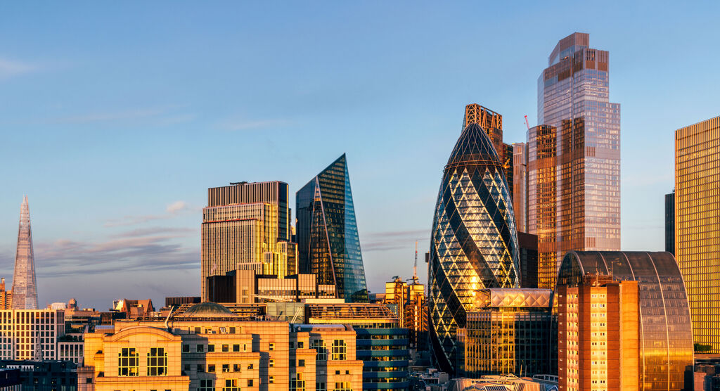 Blick auf die beeindruckende Skyline von London bei Sonnenuntergang, mit modernen Gebäuden und leuchtenden Fenstern.
