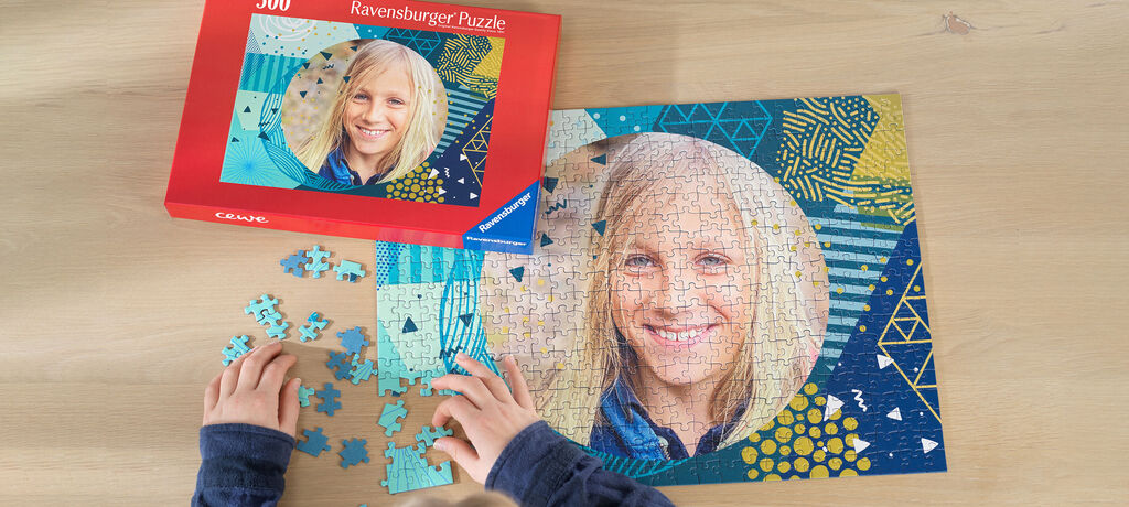 Ein Kind puzzelt ein farbenfrohes Ravensburger Puzzle auf einem Tisch, daneben liegt die Puzzle-Box