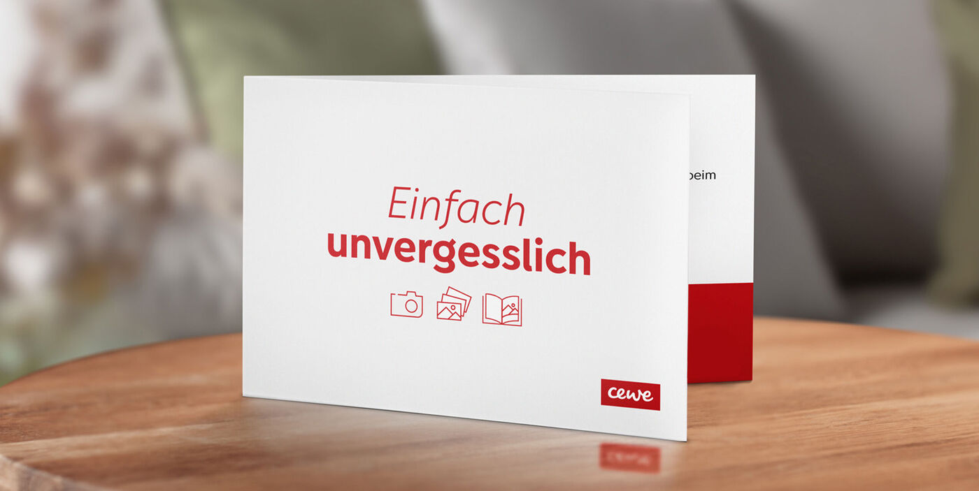 CEWE Grußkarte mit dem Text 'Einfach unvergesslich' auf einem Holztisch