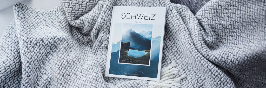 Ein CEWE FOTOBUCH liegt auf einer weichen Decke, umgeben von einer entspannenden Atmosphäre.