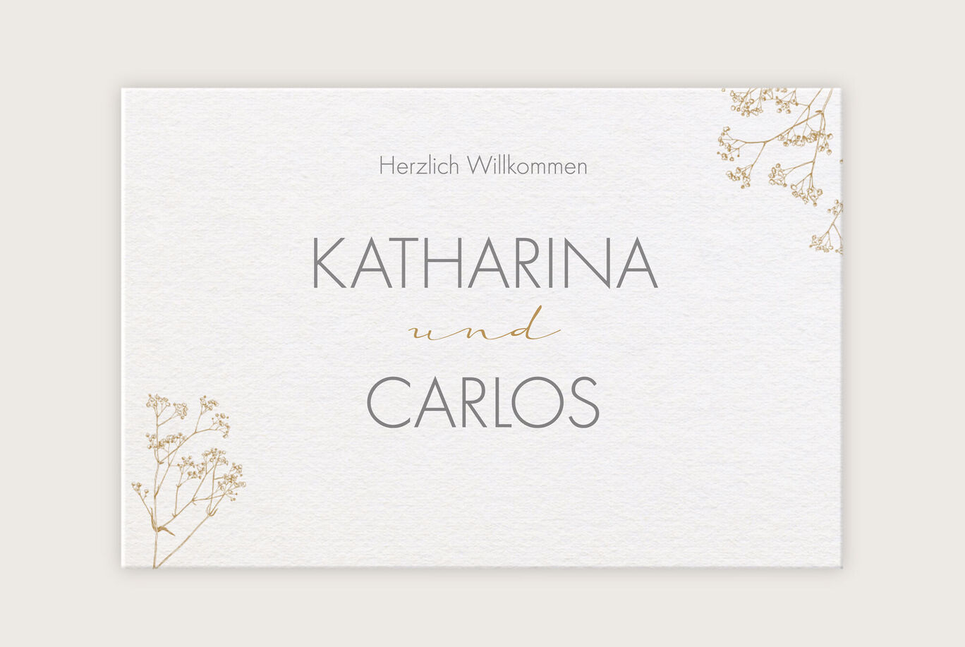 Einladungsdesign für eine Hochzeit mit Text: 'KATHARINA und CARLOS'. Elegante Schriftarten und zarte Blumenverzierungen am Rand.