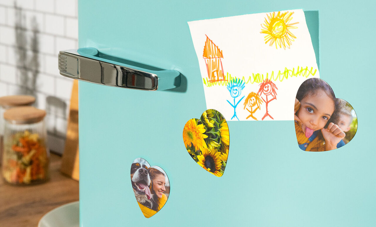 Bunte Magneten halten Fotos und eine Zeichnung an einem blauen Kühlschrank.
