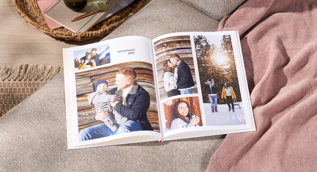 Offenes Fotobuch mit liebevollen Familienerinnerungen auf einer gemütlichen Decke