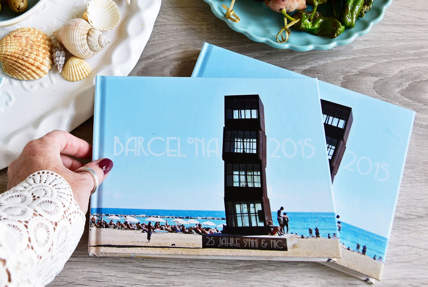 Ein Mensch hält ein CEWE Fotobuch mit einem Strandmotiv in der Hand.