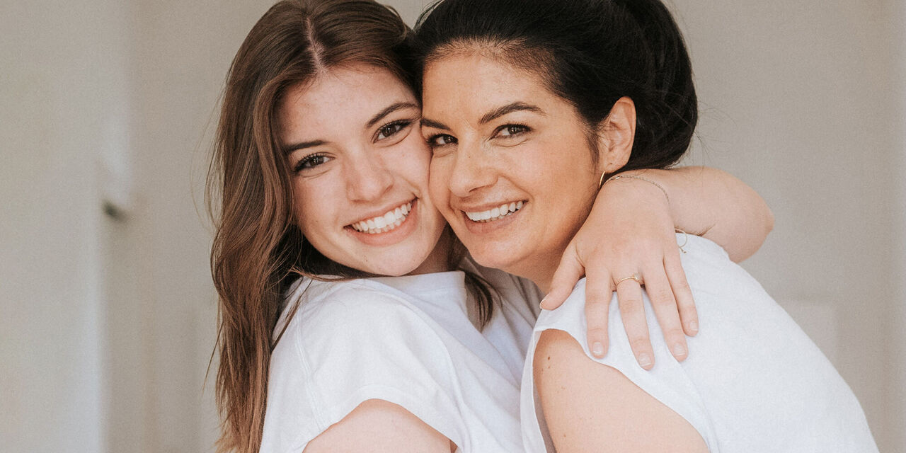 Zwei Frauen umarmen sich liebevoll und strahlen Freude aus
