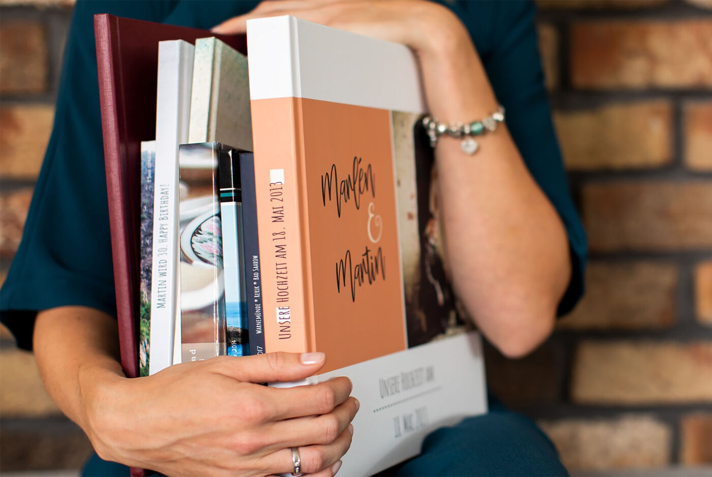 Eine Frau hält ein CEWE Fotobuch mit dem Titel "Momente & Merkmale" in den Händen und lächelt dabei.