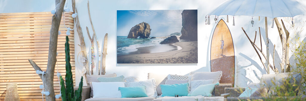 Wunderschöner Strand mit sanften Wellen und Felsen im Hintergrund, dekorativer Raum mit bequemen Kissen
