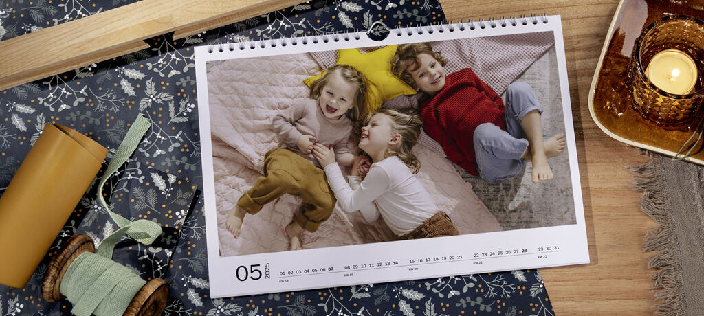 Ein Kalenderblatt mit einem Foto von 3 Kindern auf einer bunten Decke, die sich amüsieren.