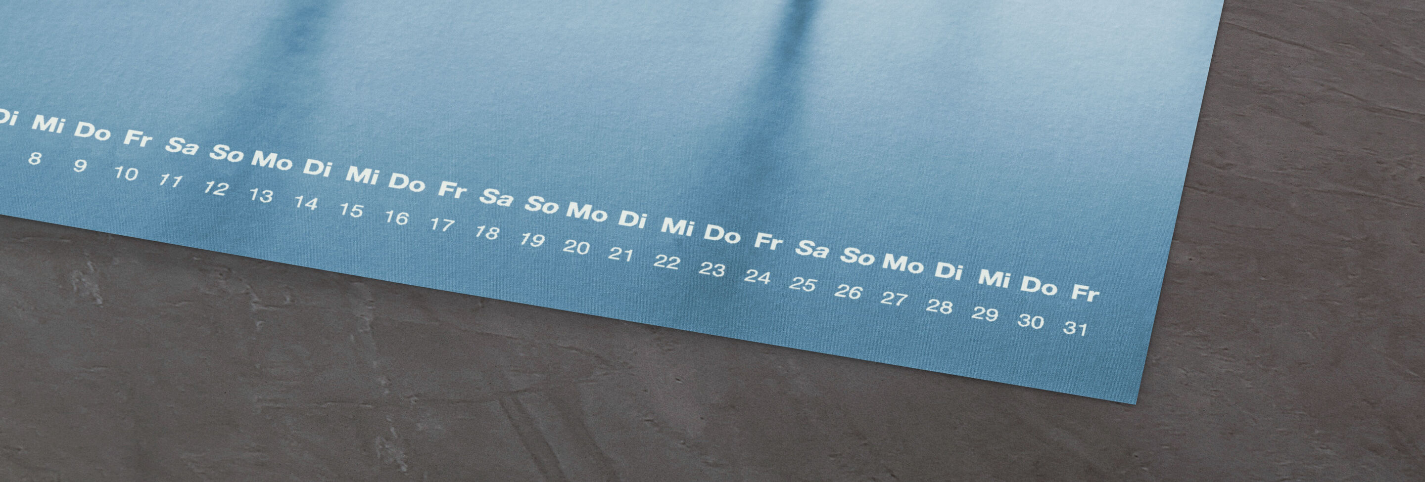 Design eines CEWE Fotokalenders mit einem blauen Hintergrund, der die Wochentage und Zahlen klar zeigt