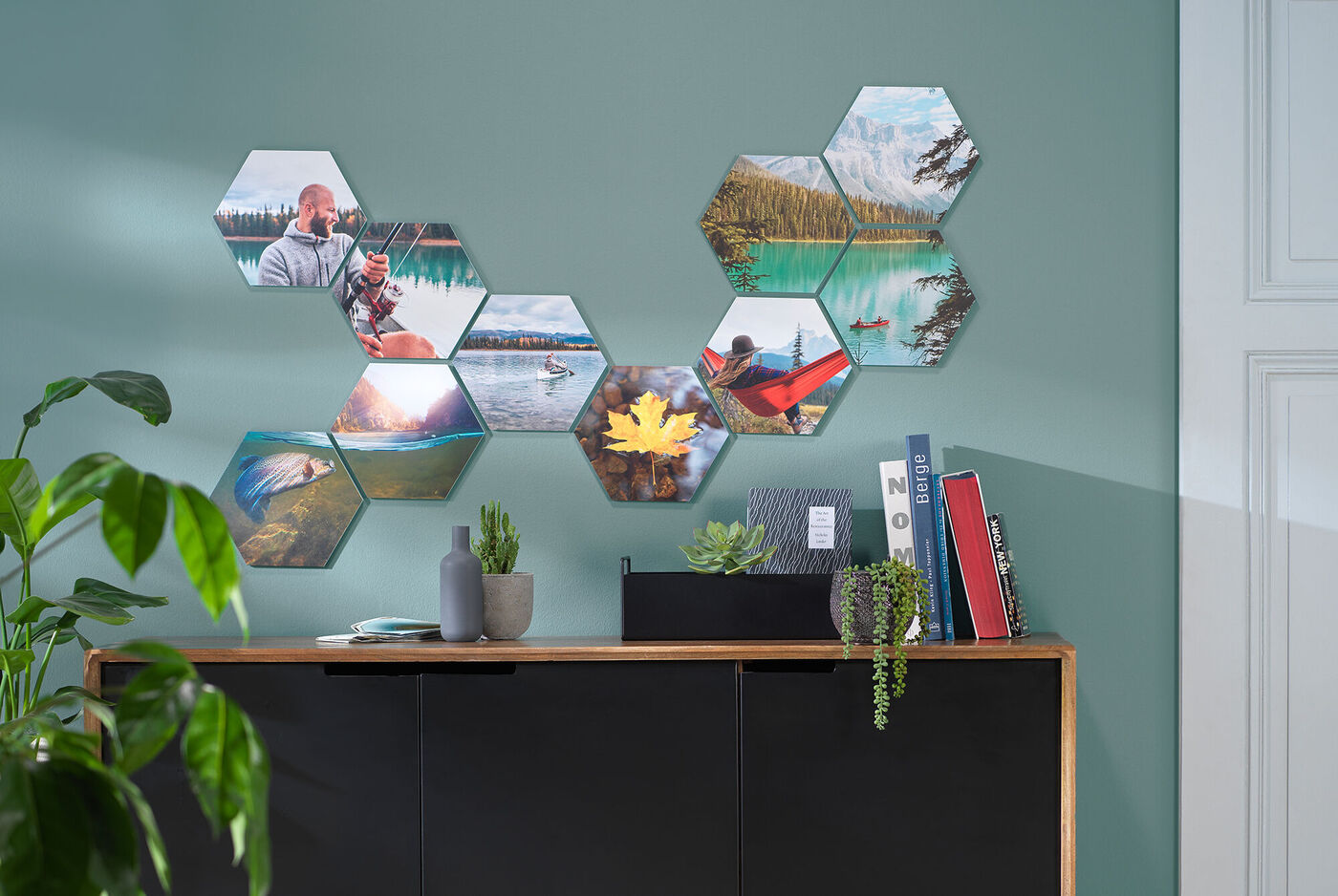 Sechsseitige Fotos in unterschiedlichen Formen an einer grauen Wand aufgereiht, darunter eine Pflanze und Dekoration.