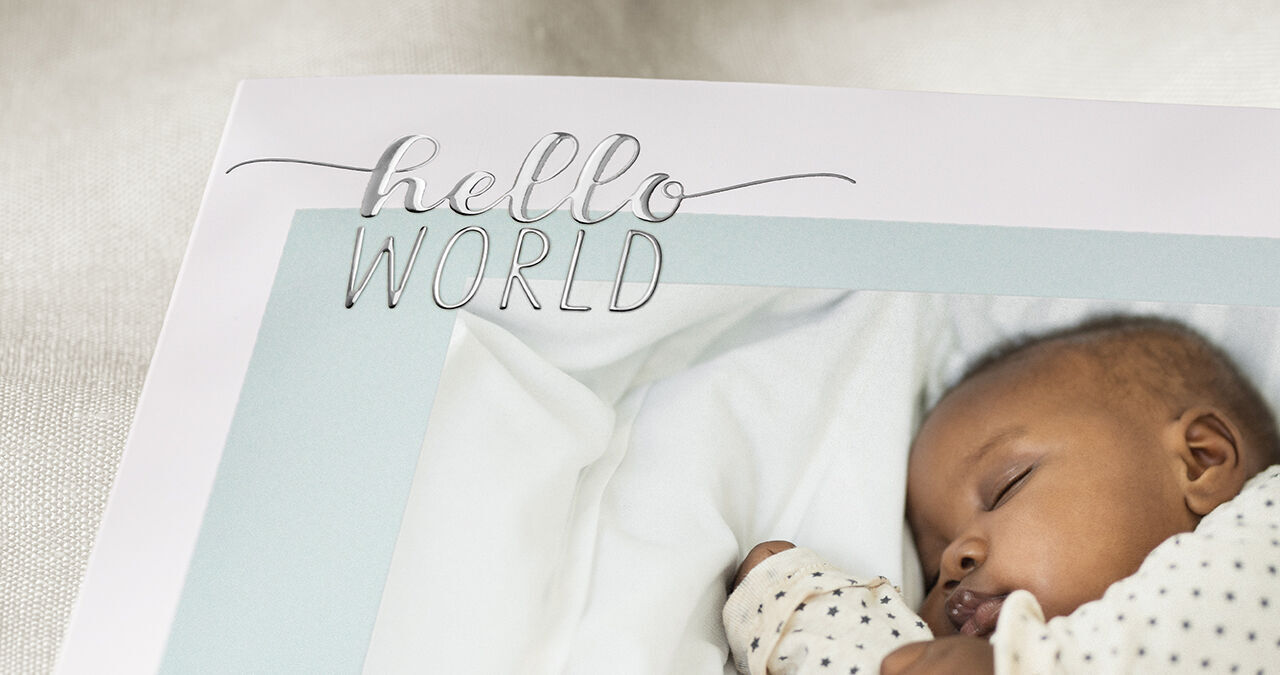 Ein liebevolles Fotobuch mit dem Titel 'hello WORLD' und einem Baby auf einer weichen Decke.