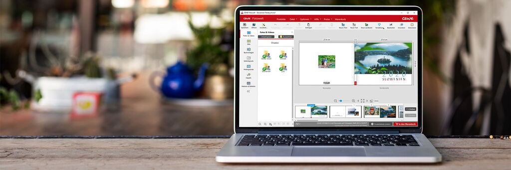 Ein Laptop zeigt die CEWE Fotobuch Software, umgeben von Pflanzen und einem Teekessel.