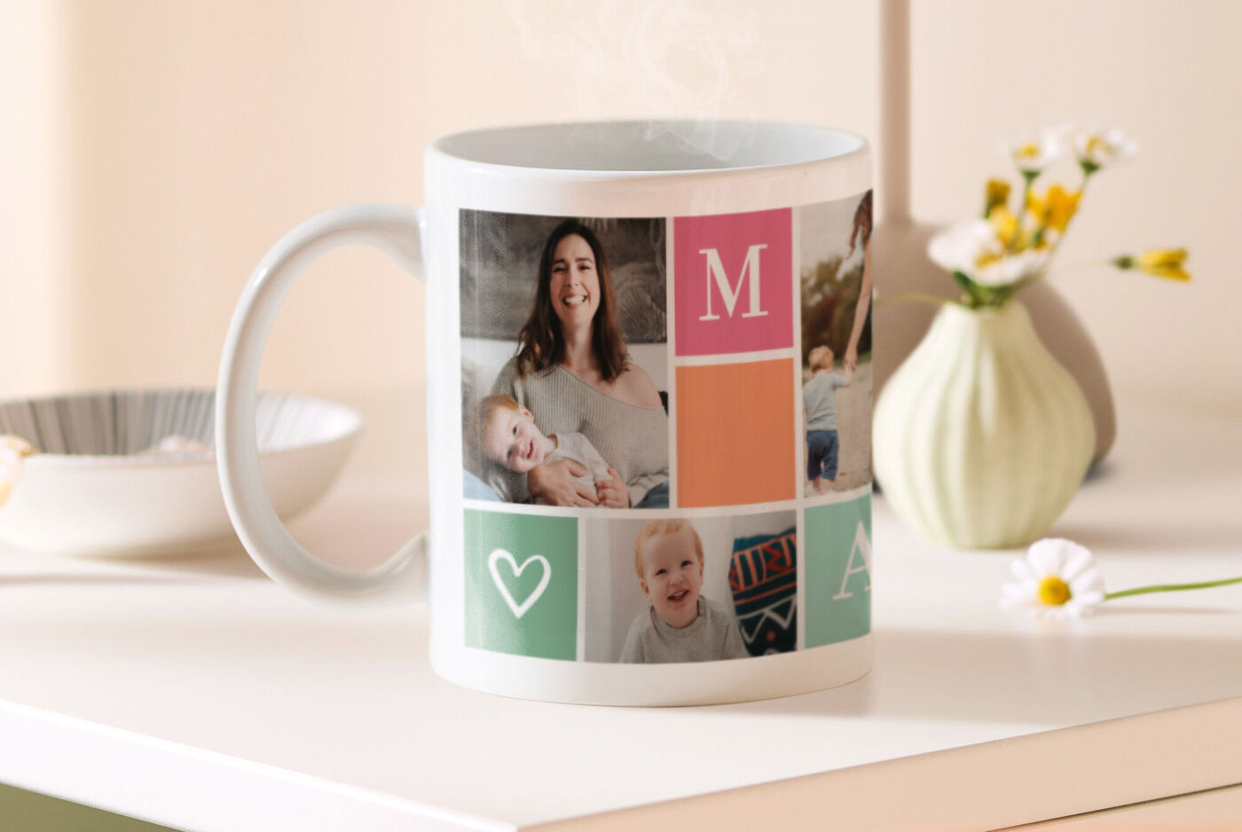 Fototasse mit bunter Collage aus Familienfotos, Buchstabe M und Herzsymbol steht auf einem Tisch