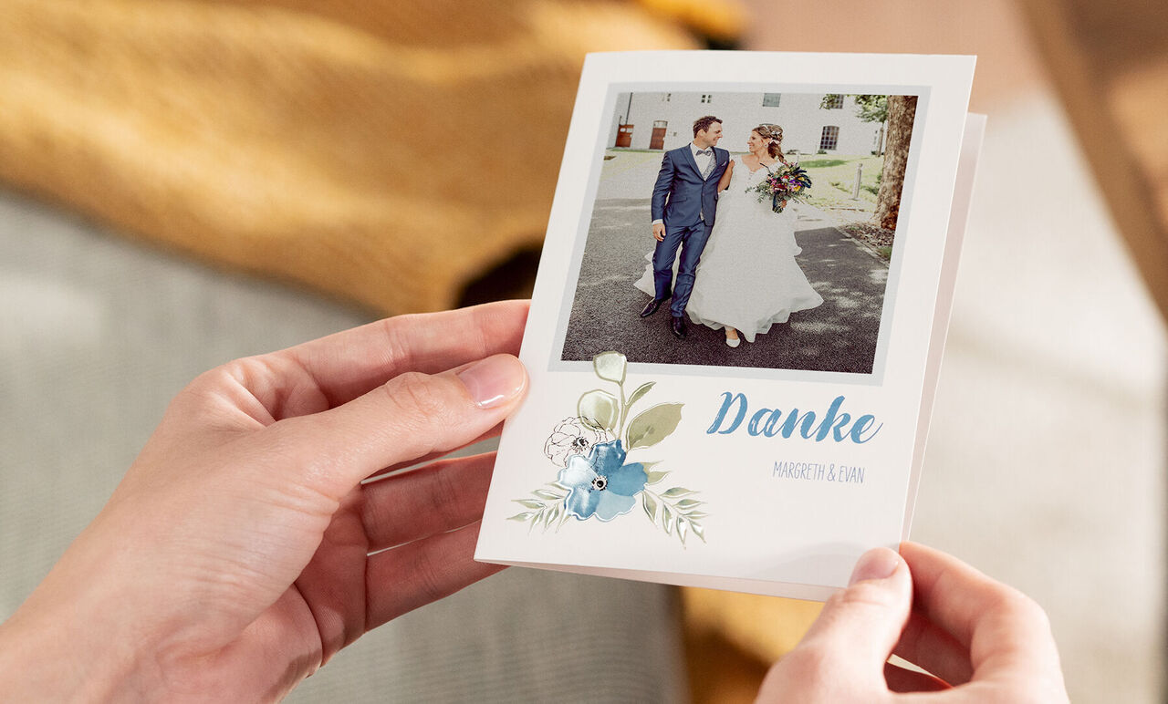 Hochzeitskarte mit dem Text 'Danke' und einem Bild von einem Brautpaar, das im Freien steht
