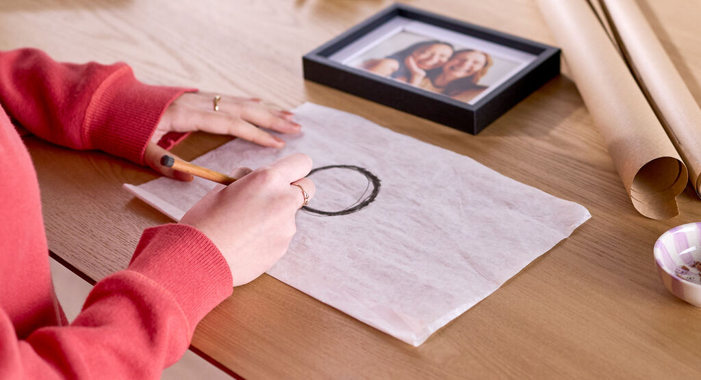 Eine Frau zeichnet mit einem dicken Bleistift einen Kreis auf Pergamentpapier.