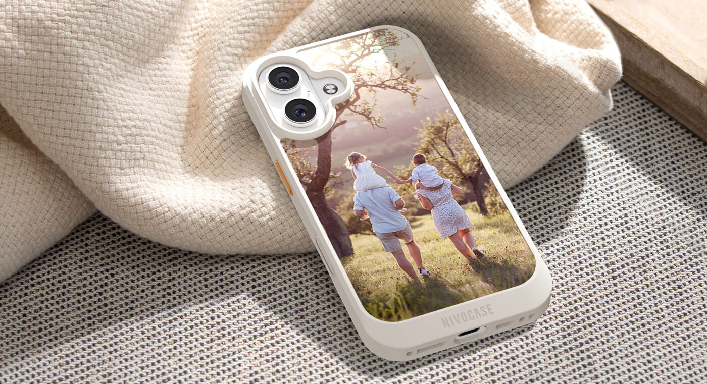 IPhone mit heller Schutzhülle liegt auf Stoff; auf der Hülle ist ein Foto von zwei Erwachsenen mit Kindern auf den Schultern beim Spaziergan