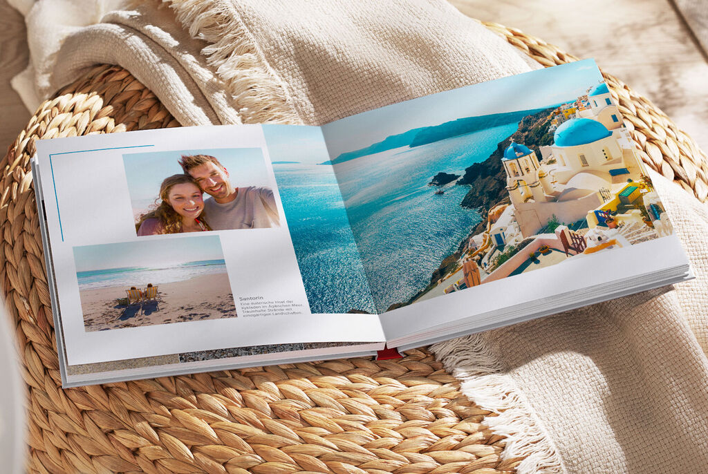 Ein aufgeschlagenes Fotobuch mit zwei Bildern von Urlaubsmomenten am Strand und einer Küstenlandschaft.