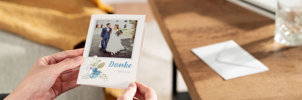 Eine Person hält eine CEWE Grußkarte mit einem Dankeschön-Text und Hochzeitsfoto in der Hand.