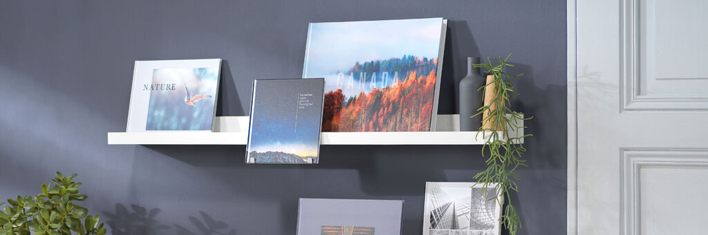 Eine stilvolle Wandregal-Dekoration mit verschiedenen CEWE Fotoprodukten, die in harmonischen Farben präsentiert werden