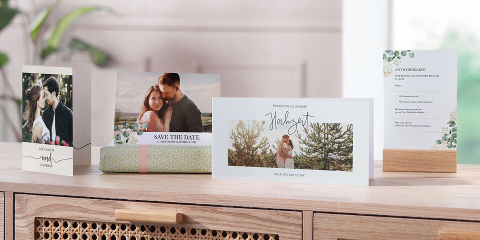 Ein schönes Set von personalisierten Hochzeits-Einladungen und Karten auf einem Holztisch, mit romantischen Fotos und frischem Design
