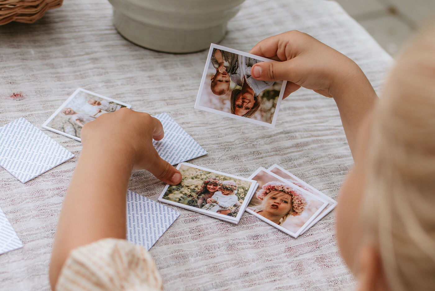 Ein Kind mit zwei Händen spielt mit Fotos und sortiert sie.