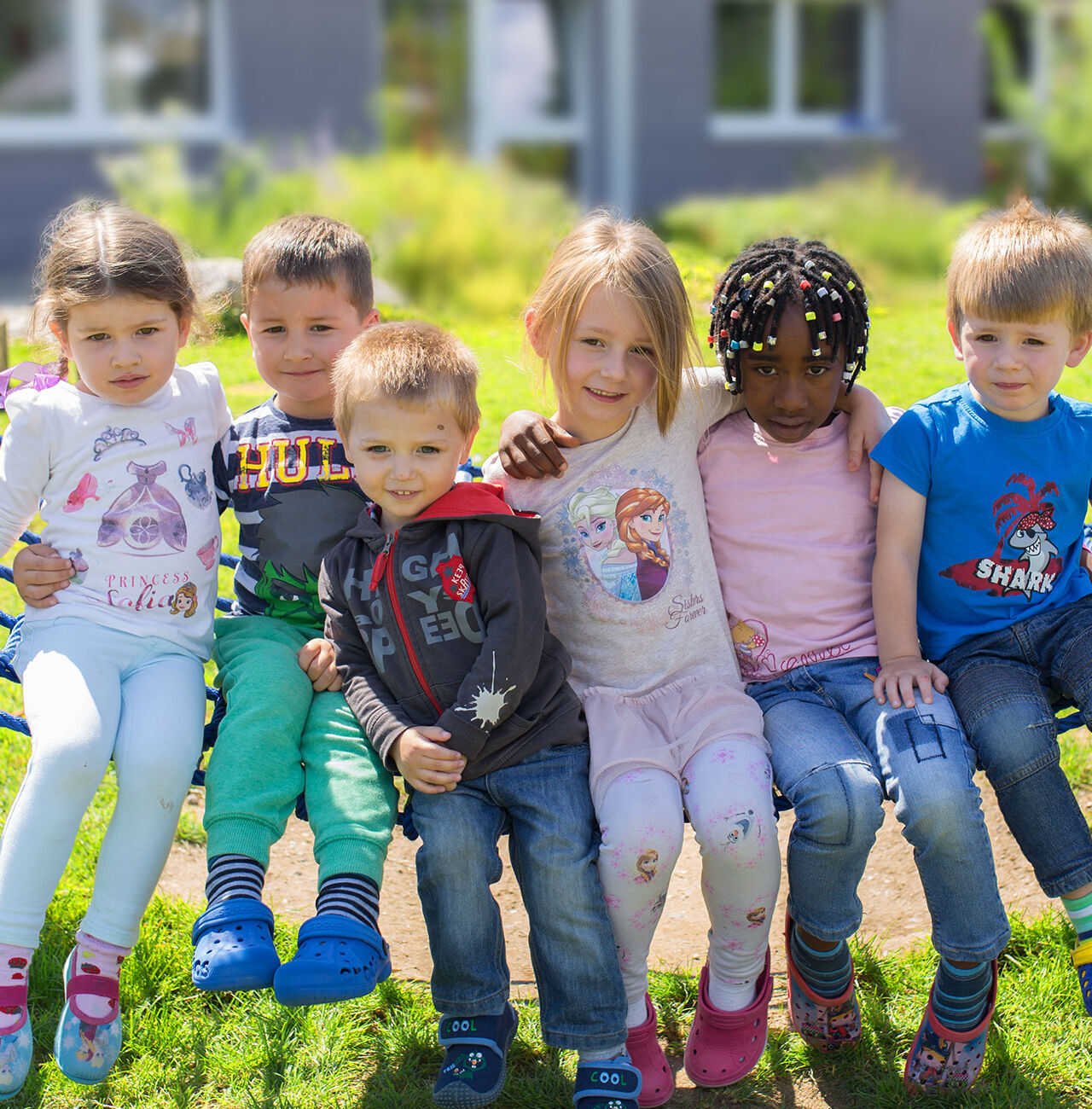 Eine Gruppe von fröhlichen Kindern sitzt zusammen im Freien und genießt den Tag.