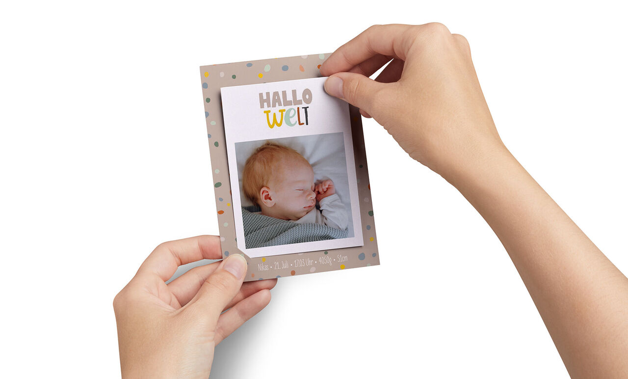 Eine Person hält eine Karte mit einem Bild und dem Text 'Hallo Welt'