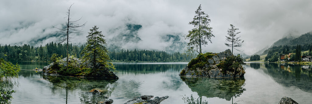 Panoramablick auf einen ruhigen See umgeben von Bäumen und Bergen