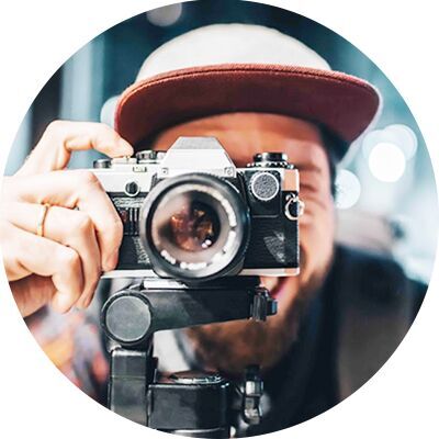 Ein lächelnder Fotograf, der eine Kamera hält, und bereit ist, einen Schnappschuss zu machen.