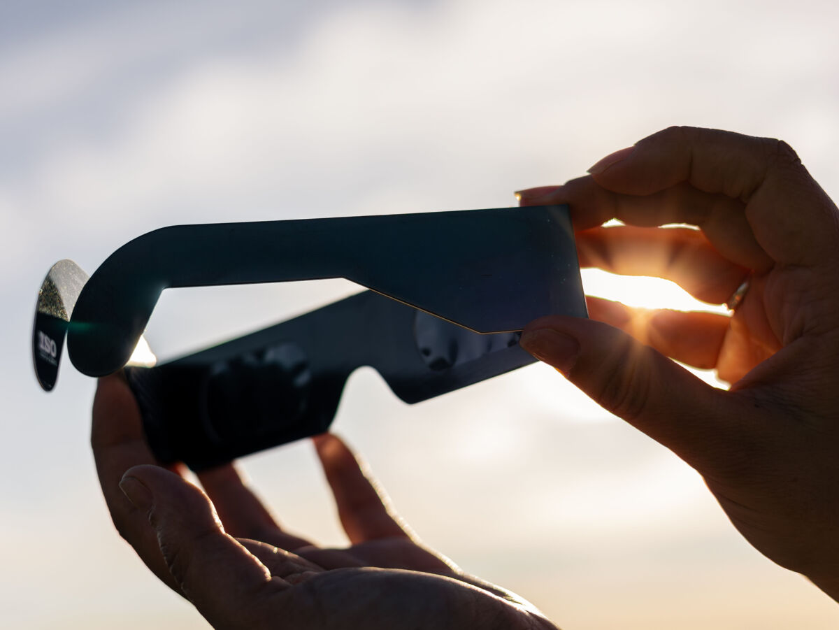 Hände, die eine Schutzbrille halten, die bei einer Sonnenfinsternis die Augen schützt.