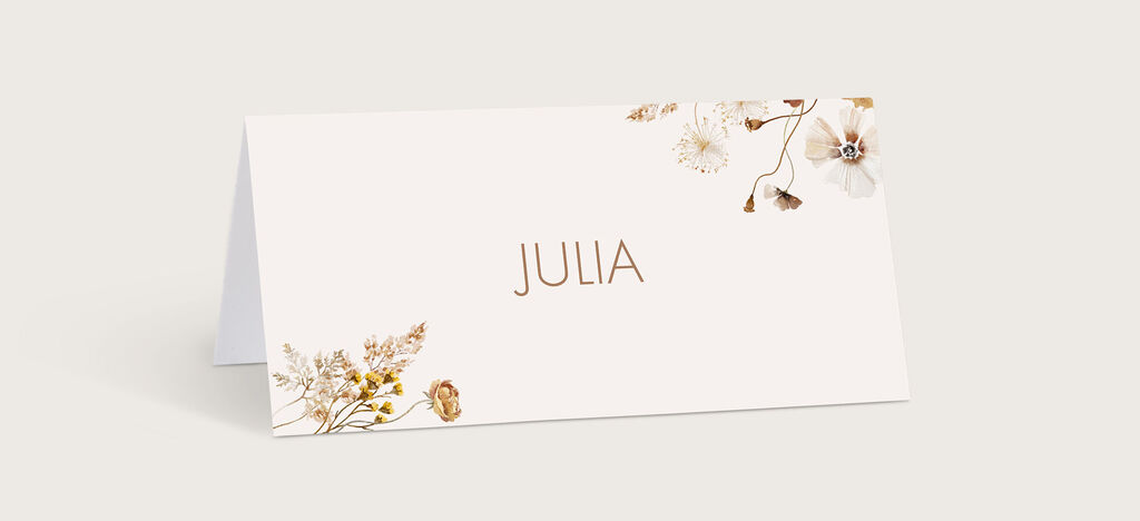 Auf einer eleganten Tischkarte steht der Name Julia, umgeben von zarten Blumenmotiven, die eine liebevolle Atmosphäre schaffen.