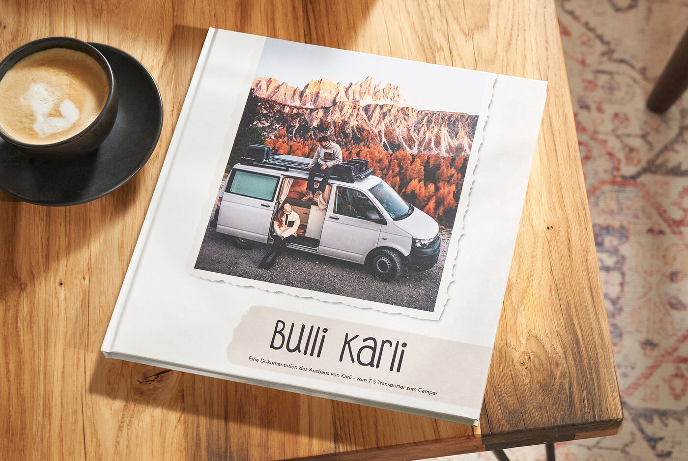 Ein Fotobuch mit dem Titel 'Bulli Karli' auf einem Tisch, neben einer Tasse Kaffee