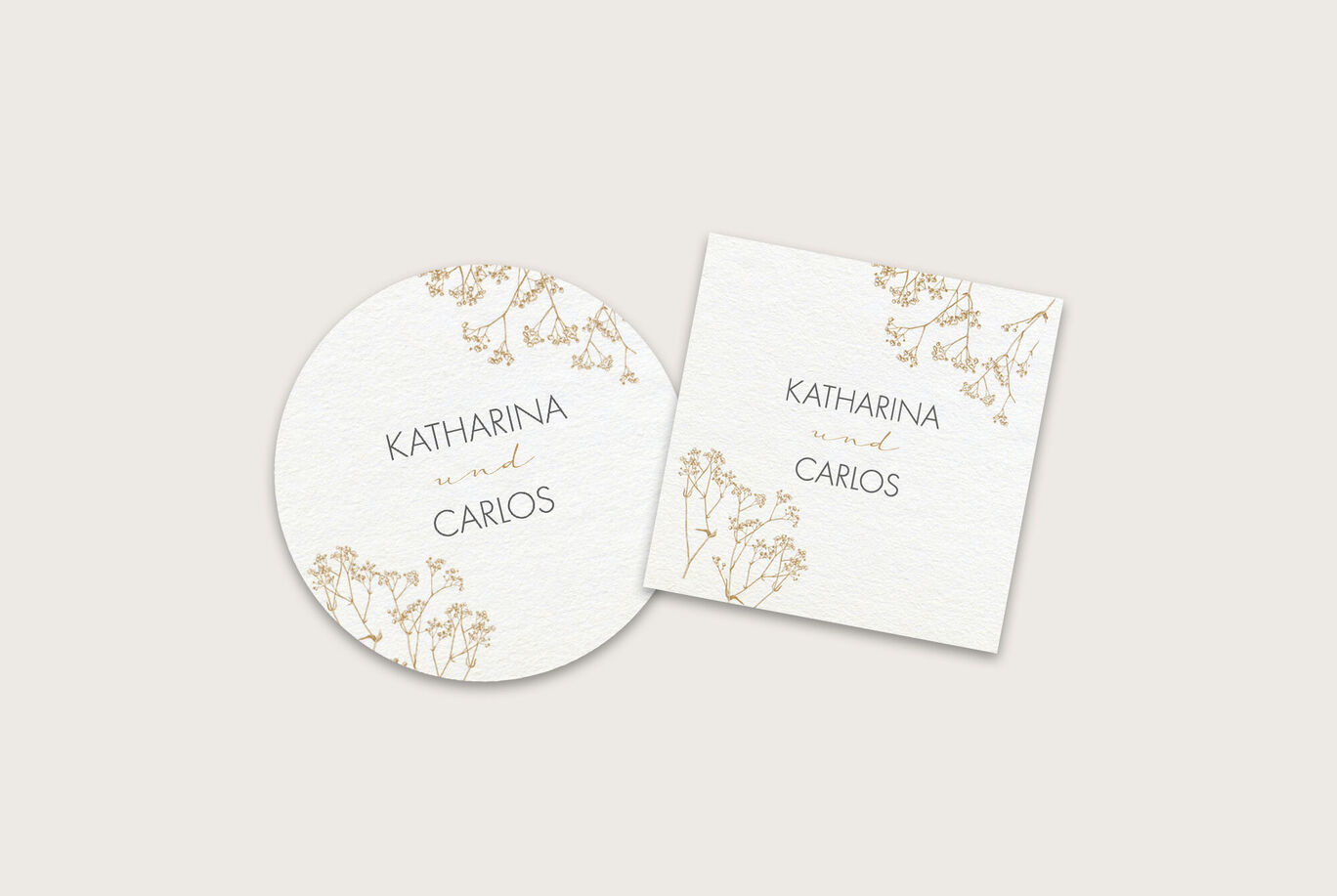 Zwei elegante Einladungskarten mit goldenen Verzierungen und den Namen Katharina und Carlos