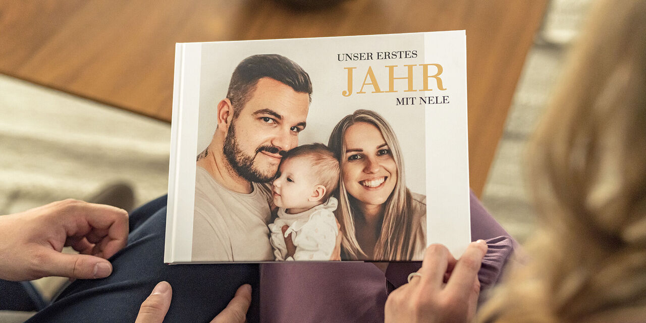 Familienfoto mit Baby in einem CEWE FOTOBUCH, dass eine liebevolle Erinnerung darstellt.