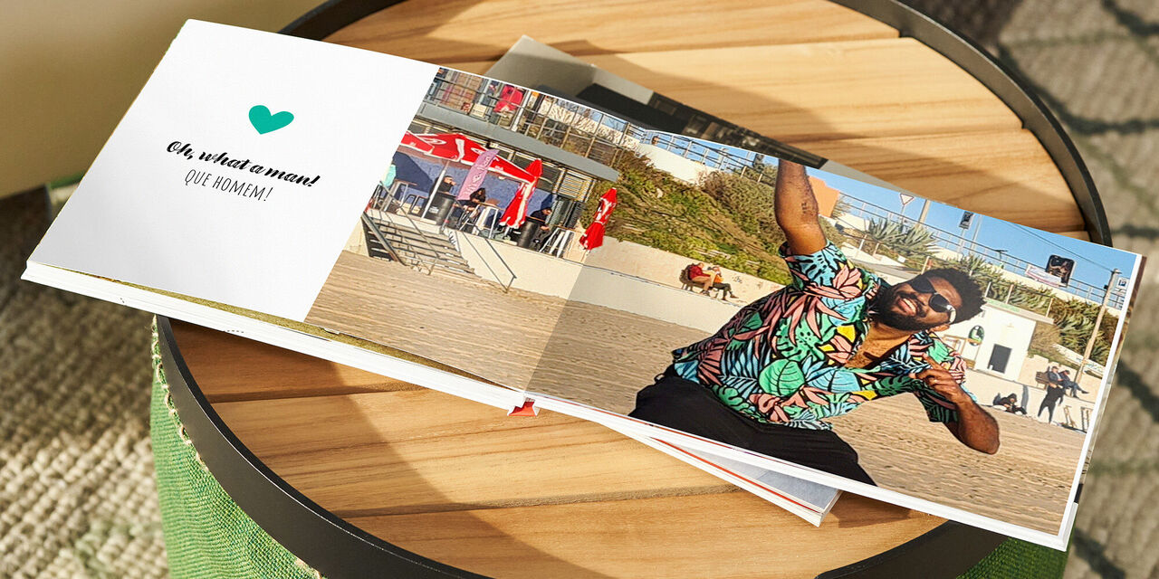 Ein Mann macht einen Fotografie-Schnappschuss mit einem CEWE FOTOBUCH am Strand.